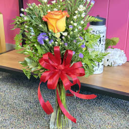 Orange rose bouquet in a clear glass vase with a red ribbon