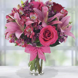 Pink and purple bouquet of lilies, roses, and alstroemeria in a glass vase