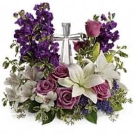 Purple and pink floral arrangement with white lilies and roses in a clear vase