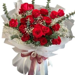 Bouquet of red roses wrapped in white paper with a ribbon
