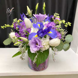 Purple and white floral arrangement in a mosaic glass vase