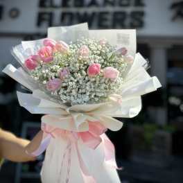 Pink tulip bouquet with baby's breath wrapped in white paper and ribbon