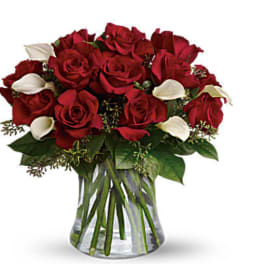 Bouquet of red roses with white calla lilies in a clear glass vase