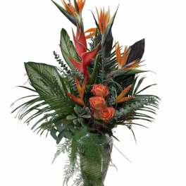 Tropical bouquet with orange bird of paradise and roses in a glass vase