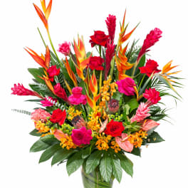 Tropical bouquet with red roses and orange bird-of-paradise in a glass vase