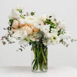 White and blush flowers arranged in a clear glass vase