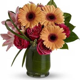 Bouquet of peach gerbera daisies and pink roses in a green glass vase