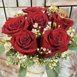 Red roses arranged in a white hat box with small white filler flowers