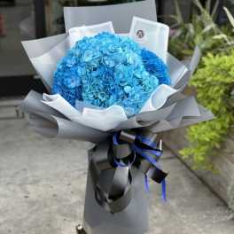 Bright blue hydrangea bouquet wrapped in gray paper with black ribbon