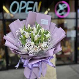 Lavender-wrapped bouquet of white tulips and small purple flowers