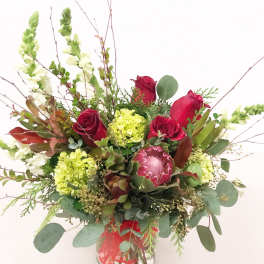 Bouquet of red roses and green blooms in a glass vase