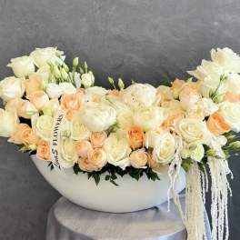 Cream and peach roses arranged in a white bowl-shaped vase