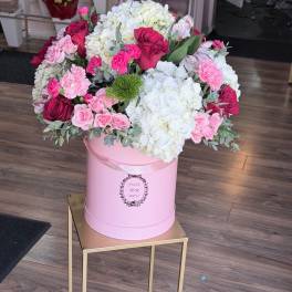 Pink and white flower arrangement in a round pink box