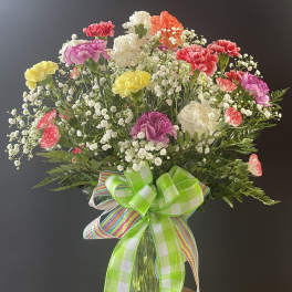 Colorful carnation bouquet in a glass vase with a large ribbon bow