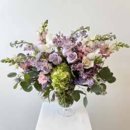 Pastel bouquet of roses, hydrangea, and orchids in a glass vase