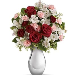 Red roses, pink carnations, and white alstroemeria in a glass vase