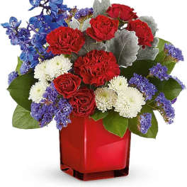 Red roses, white chrysanthemums, and blue flowers in a red vase