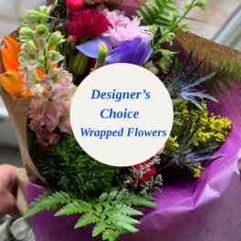 Wrapped bouquet of mixed colorful flowers with a designer's choice label