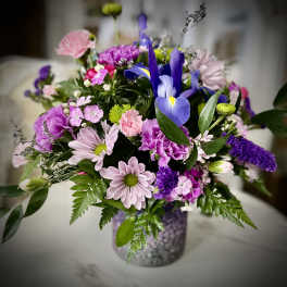 Mixed bouquet of purple, pink, and white flowers in a glittery vase