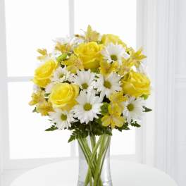 Yellow roses and white daisies in a clear glass vase