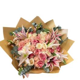 Bouquet of pink and cream roses with lilies wrapped in brown paper