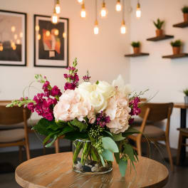 Pink and white floral arrangement in a clear glass vase on a table