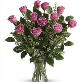 Pink roses arranged in a clear glass vase with mixed greenery