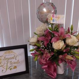 Pink lilies and white roses in a vase with a birthday balloon