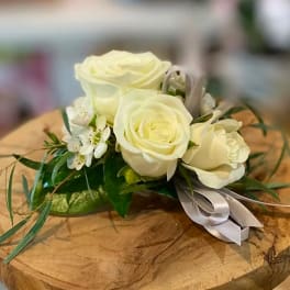White rose corsage with small white blossoms and a silver ribbon