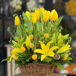 Yellow tulips and lilies arranged in a wicker basket