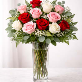 Bouquet of red, pink, and white roses in a clear glass vase