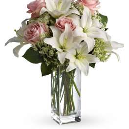 Tall glass vase with white lilies and pale pink roses