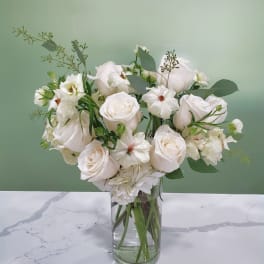 White roses and small white blooms in a clear glass vase