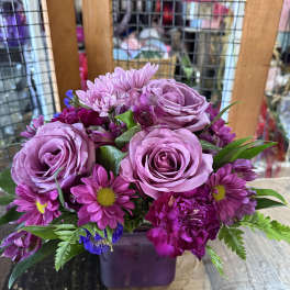 Purple rose and daisy bouquet in a square vase