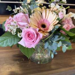 Pink roses and a peach gerbera daisy in a glass vase