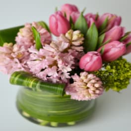 Pink tulips and pale pink flowers in a green glass vase