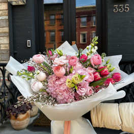 Large pink bouquet wrapped in white paper with a peach ribbon