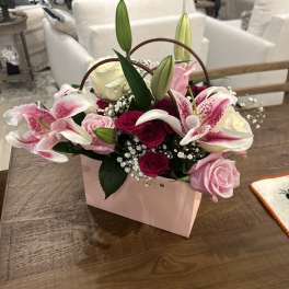 Pink and white lilies and roses in a pink handled box