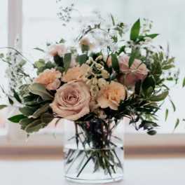 Blush roses and peach carnations in a clear glass vase