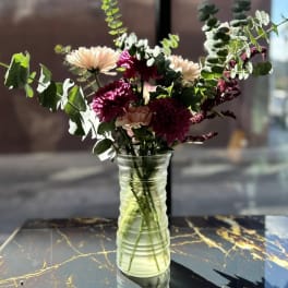 Mixed bouquet of pink and cream flowers in a clear glass vase