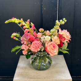 Pink and peach flowers arranged in a clear glass vase