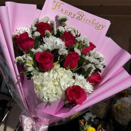Bouquet of red roses and white flowers in pink wrapping with a Happy Birthday card