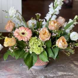 Peach roses and a pink gerbera daisy in a low vase arrangement