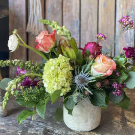 Mixed bouquet in a small white vase with pink and peach roses