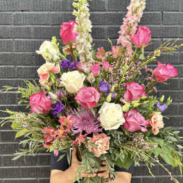 Large mixed bouquet of pink, white, and purple flowers in a glass vase