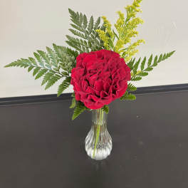 Red rose arrangement in a clear glass vase with fern and yellow filler
