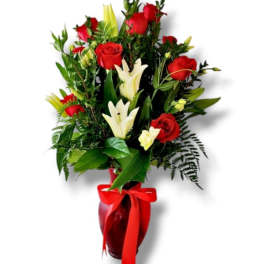 Red roses and white lilies in a red vase with a ribbon
