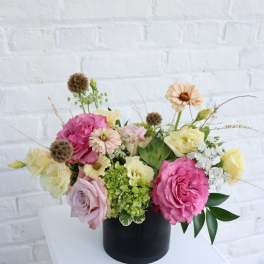 Pink and cream roses arranged in a black vase