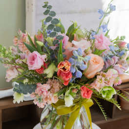 Mixed pastel bouquet in a glass vase with a yellow ribbon