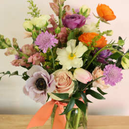 Mixed bouquet in a glass vase with orange, purple, and blush flowers
